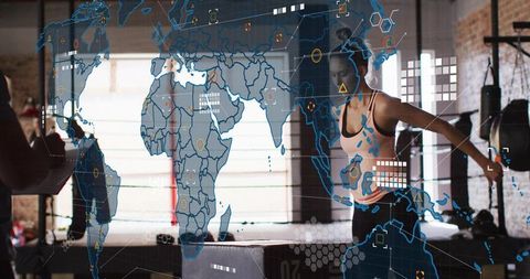 Athletic woman jumping on plyometric box with augmented reality world map HUD in gym studio