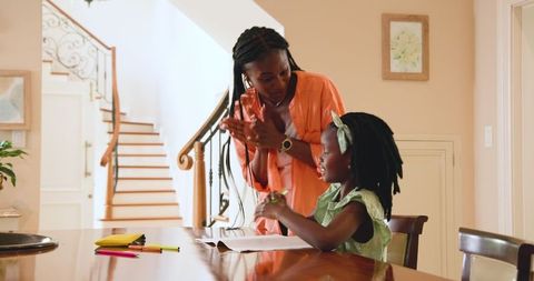 Mother helping daughter with homework at kitchen table