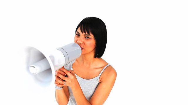 Captivating image of an Asian woman using a megaphone to announce something with enthusiasm. Perfect for marketing materials related to communication campaigns, public speaking, and social awareness messages. Ideal for conveying themes of expressing or spreading a message effectively.