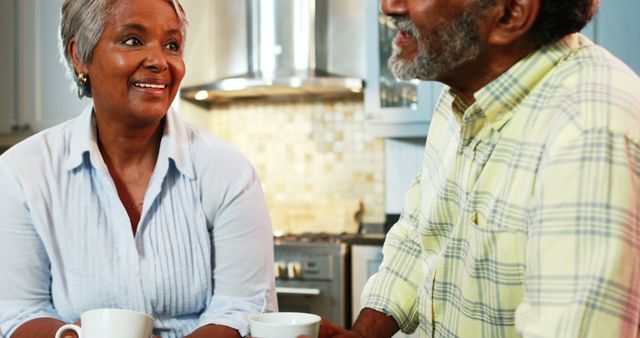 Senior couple having coffee in kitchen at home