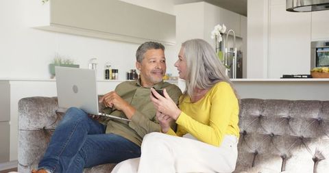 Mature couple relaxing with technology devices on lounge sofa