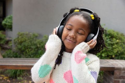 Joyful African American Girl Listening to Music Outdoors