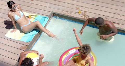 Diverse friends relaxing in pool with floats and drinks
