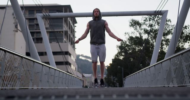 Caucasian man skipping on skipping rope on bridge in city. Sports, fitness, healthy living and outdoor activities, unaltered.
