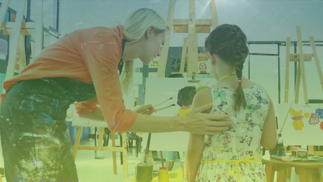 A teacher assists a young girl in an art class, fostering creativity and learning. Ideal for use in educational materials, advertisements for art schools, parenting articles, and content promoting creativity and childhood development.