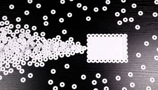 Minimalist black and white scalloped frame made from paper rings surrounding blank card on wood