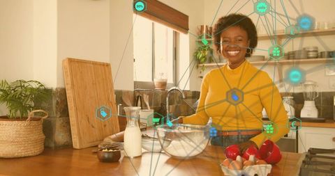 Smiling black woman preparing meal in sunlit kitchen using augmented reality recipe interface