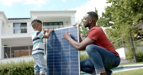 Father and Son Installing Solar Panel at Home Promoting Green Energy