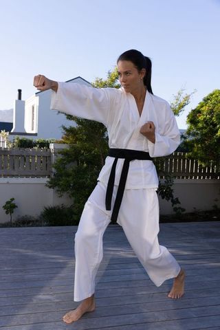 Woman Demonstrating Karate on Deck in Backyard Setting