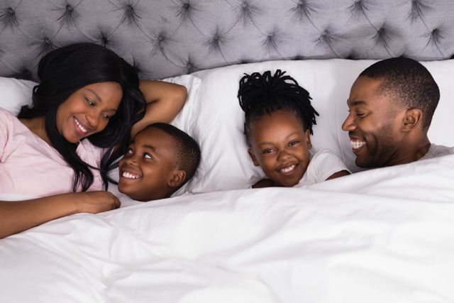 Portrait of girl lying with happy family on bed - Download Free Stock Photos Pikwizard.com