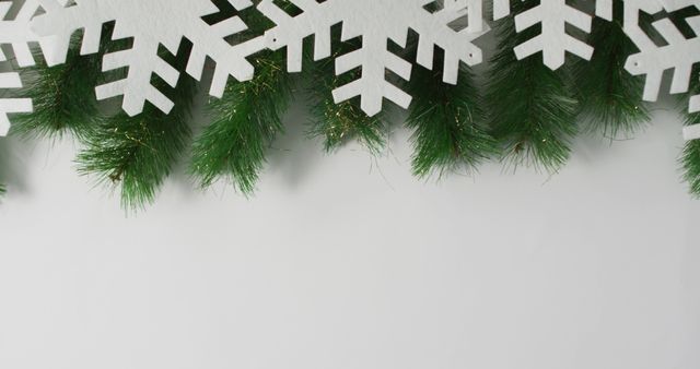 Ideal for holiday greetings, seasonal banners, or festive invitations. This image of snowflakes and pine branches against a white background evokes the spirit of the holiday season and winter festivities.