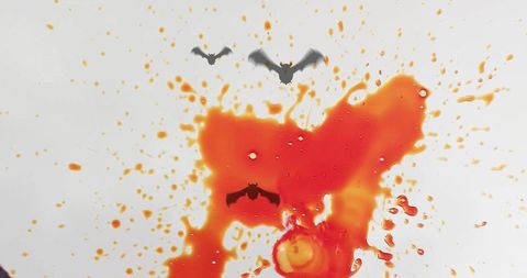 Orange red liquid splatter featuring flying bat silhouettes halloween horror background