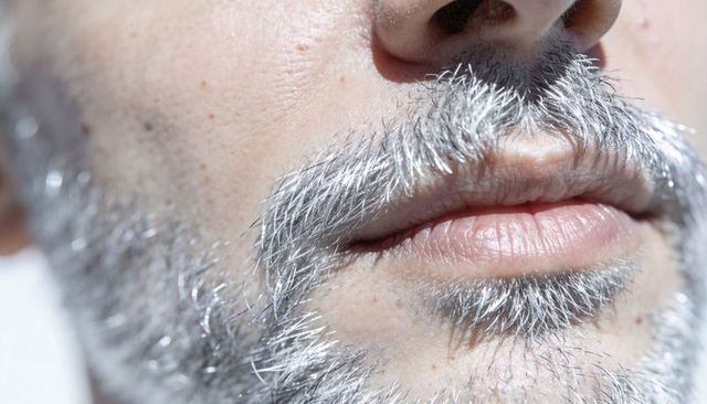 Close-up showing salt-and-pepper stubble and mustache highlighting lips and skin texture