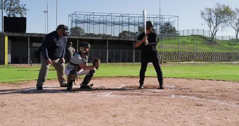 Batter Waiting at Plate with Catcher Presenting Mitt and Umpire Overseeing Game on Baseball Field