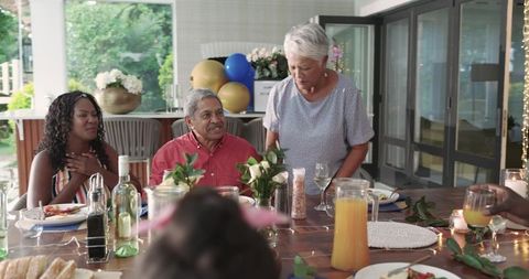 Multi-generational family sharing celebratory dinner on covered patio with warm lighting