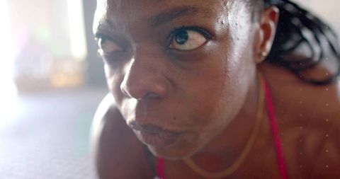 Focusing mid-adult black woman sweating during intense home workout close-up with braids