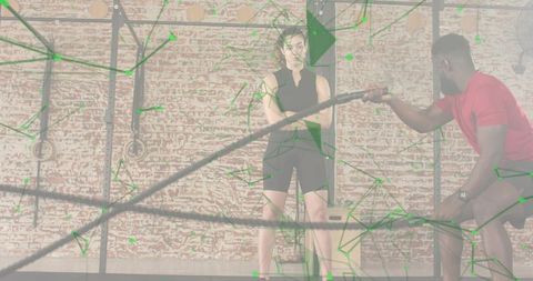 Woman standing listening to trainer coaching with battle ropes and plyo box, green overlay