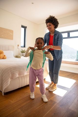 Mother Helping Daughter with Backpack in Cozy Bedroom