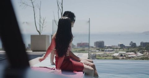 Couple relaxing at rooftop infinity pool enjoying sea view and city skyline luxury escape