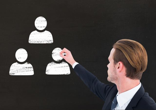 Digital composition of businessman drawing user icons with chalk on blackboard