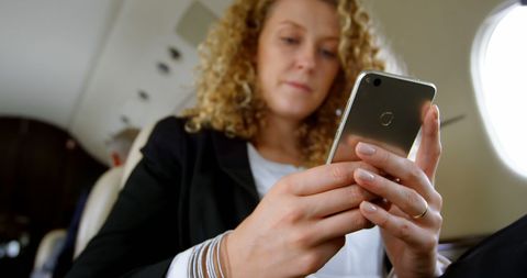 Businesswoman using smartphone in private jet