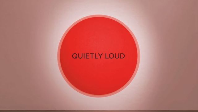 Glowing red circle with quietly loud typography on pink wall minimal backlit artwork