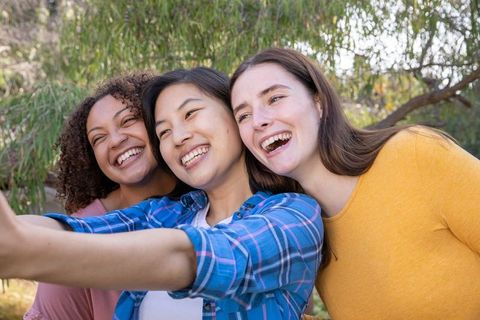 Three Diverse Female Friends Smiling and Taking Selfie Outdoors