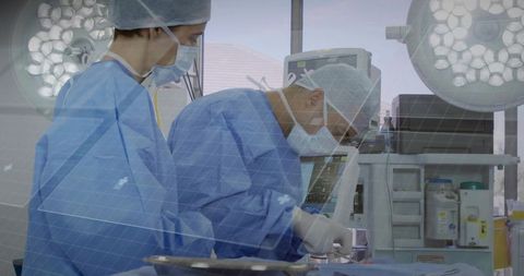 Surgeons performing surgery in modern operating room wearing sterile gowns and masks