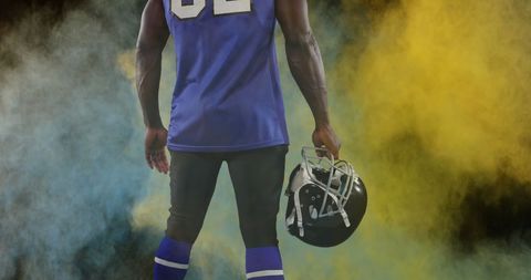 Back view of american football player with helmet and colorful smoke