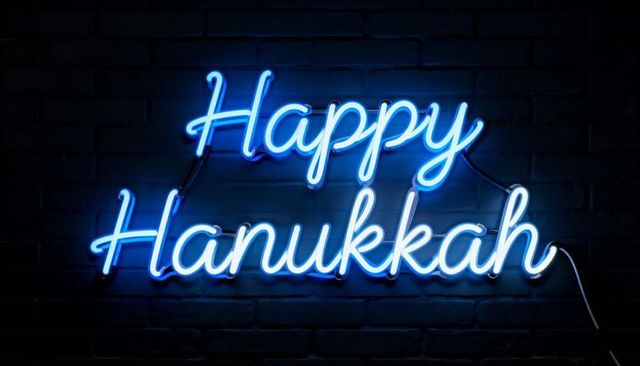 Glowing blue neon happy hanukkah script sign casting cyan light on dark brick wall