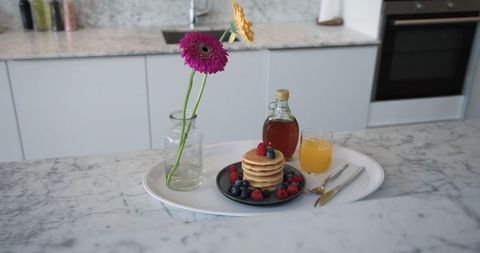 Elegant Breakfast Pancakes with Berries and Flowers in Modern Kitchen