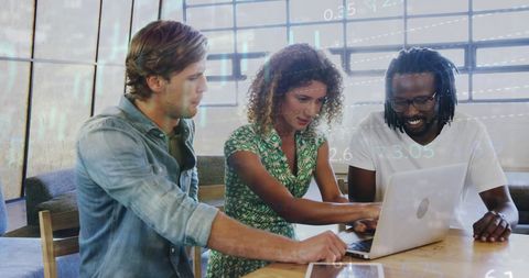 three business professionals are examining financial data on a laptop, showcasing effective teamwork and collaboration in a modern office environment. the visible market graphs symbolize data analysis and strategic planning. useful for articles on diversity in the workplace, teamwork strategies, or stock market analysis studies.