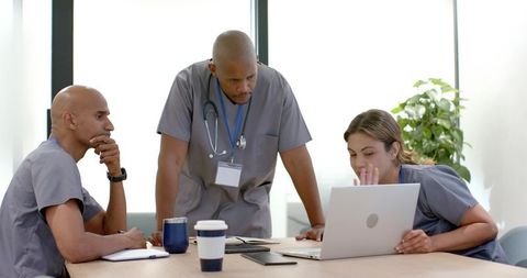 Healthcare team collaborating over laptop during patient case review