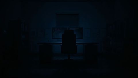 Dark Office Showing Backlit Monitors and High-Back Chair Silhouetting at Night