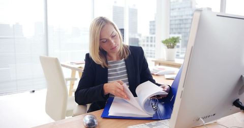 Focused Businesswoman Reviewing Documents at Modern Office Desk - Download Free Stock Images Pikwizard.com