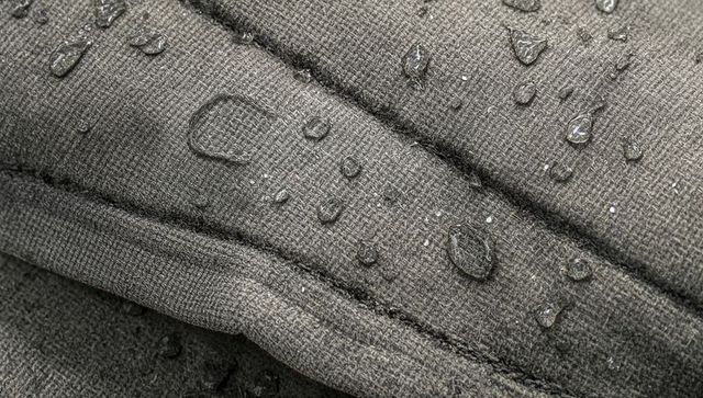 Water-repellent quilted fabric close-up showing droplet beading on padded jacket material