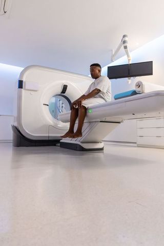 Patient sitting on ct scanner table in modern radiology suite preparing for ct scan