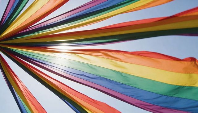 Fluttering rainbow streamers radiating from mast with sun flare for festival pride banner