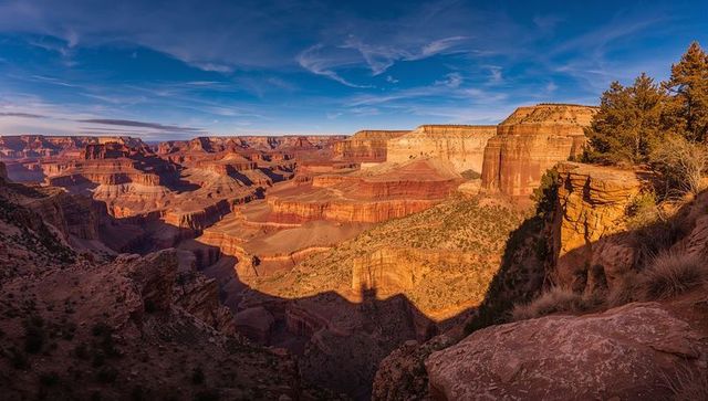 Golden hour grand canyon panorama showing layered cliffs and sunlit canyon rim