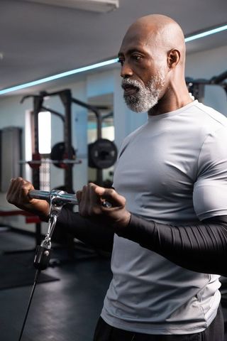 Senior african american man performing cable bicep curl focused on strength and form