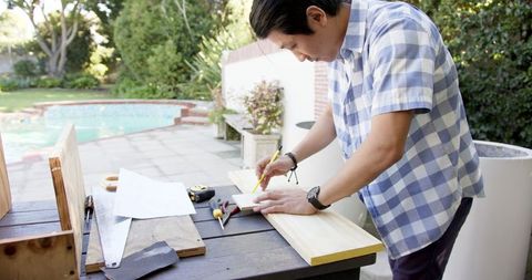 Teen Craftsman Measuring Wood at Outdoor Patio Workbench