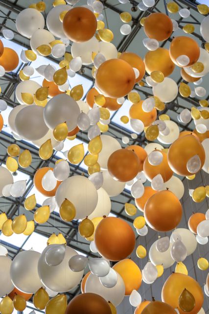 Modern space with orange, white, and yellow balloons artistically floating from the ceiling. Creates a cheerful, festive atmosphere, perfect for celebrations, parties, corporate events, or interior design inspiration.