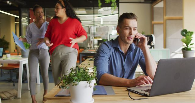 Focused Man Talking on Phone, Women Discussing in Background Modern Office - Download Free Stock Images Pikwizard.com