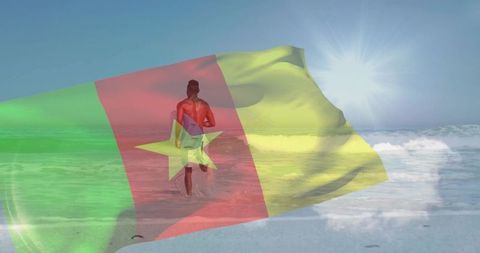 Surfer walking into ocean carrying surfboard with cameroon flag overlay, sunlit beach