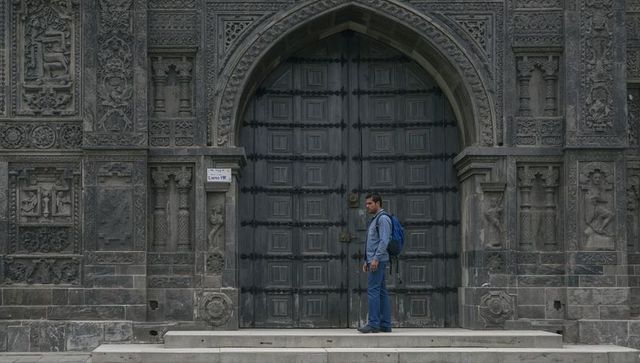 Traveler standing at ornate gothic doorway with backpack on stone steps