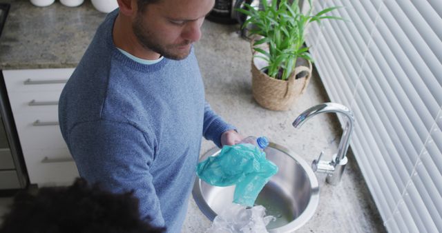 Man sorting recyclable materials in modern kitchen - Download Free Stock Images Pikwizard.com