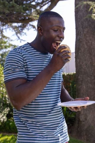 Man Enjoying Delicious Sandwich Outdoors under Sunny Sky