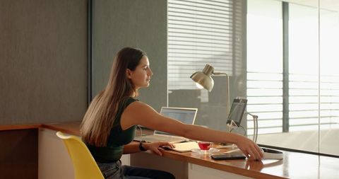 Woman working with laptop and tablet at modern desk