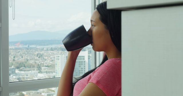 Woman enjoying coffee with city view from modern apartment - Download Free Stock Images Pikwizard.com