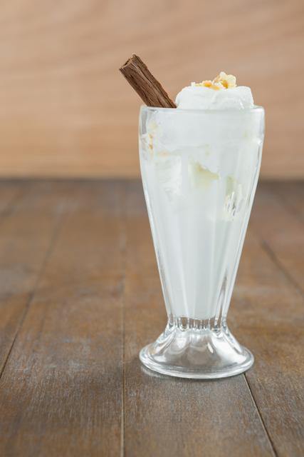 Tempting dessert featuring vanilla ice cream served in a tall glass with a chocolate stick garnish. Ideal for use in food blogs, dessert menus, and culinary presentations focusing on sweet treats and indulgent desserts. Visually appealing for social media posts about desserts and ice cream.